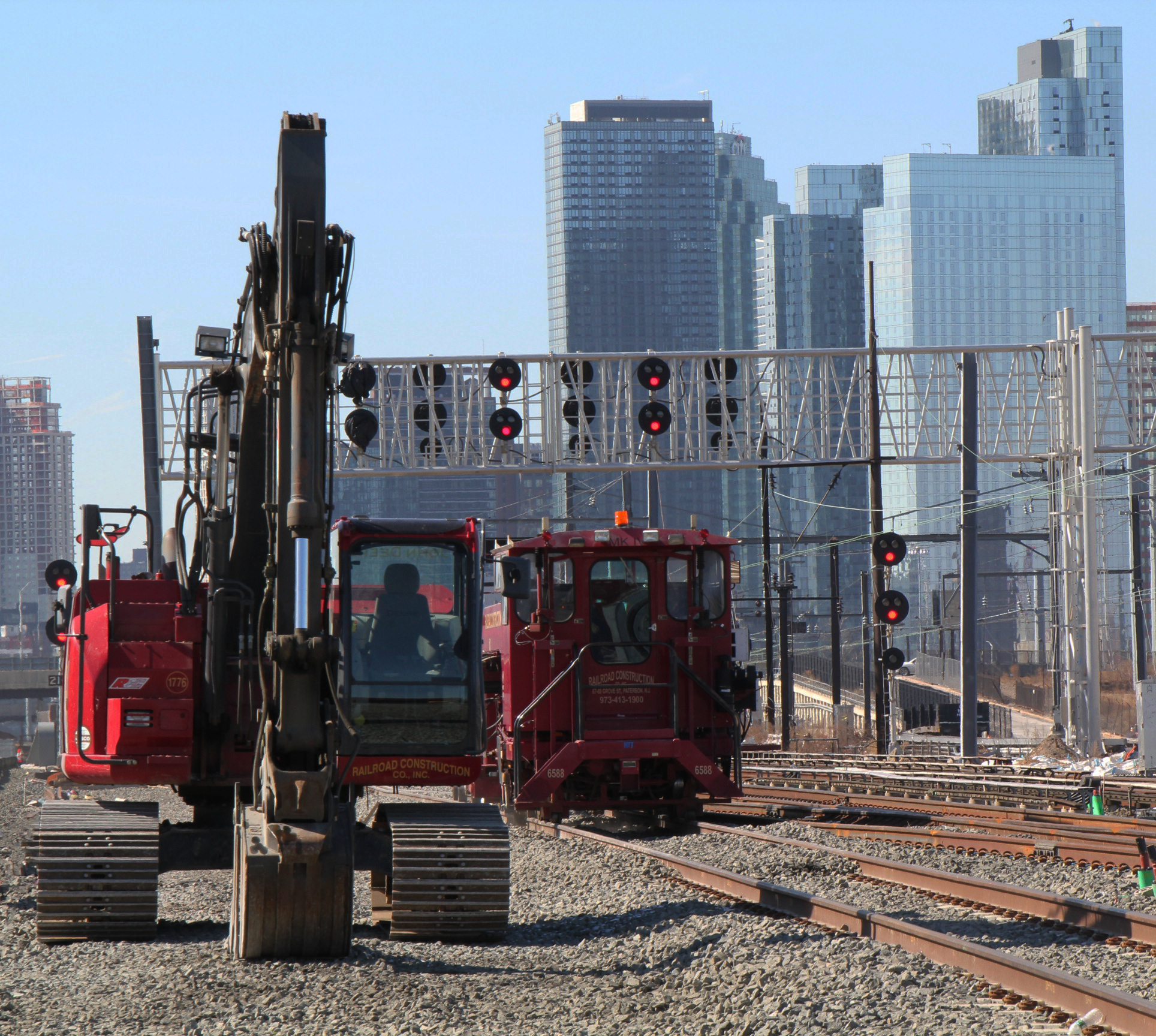 Red railroad construction company machinery with city building view in the background