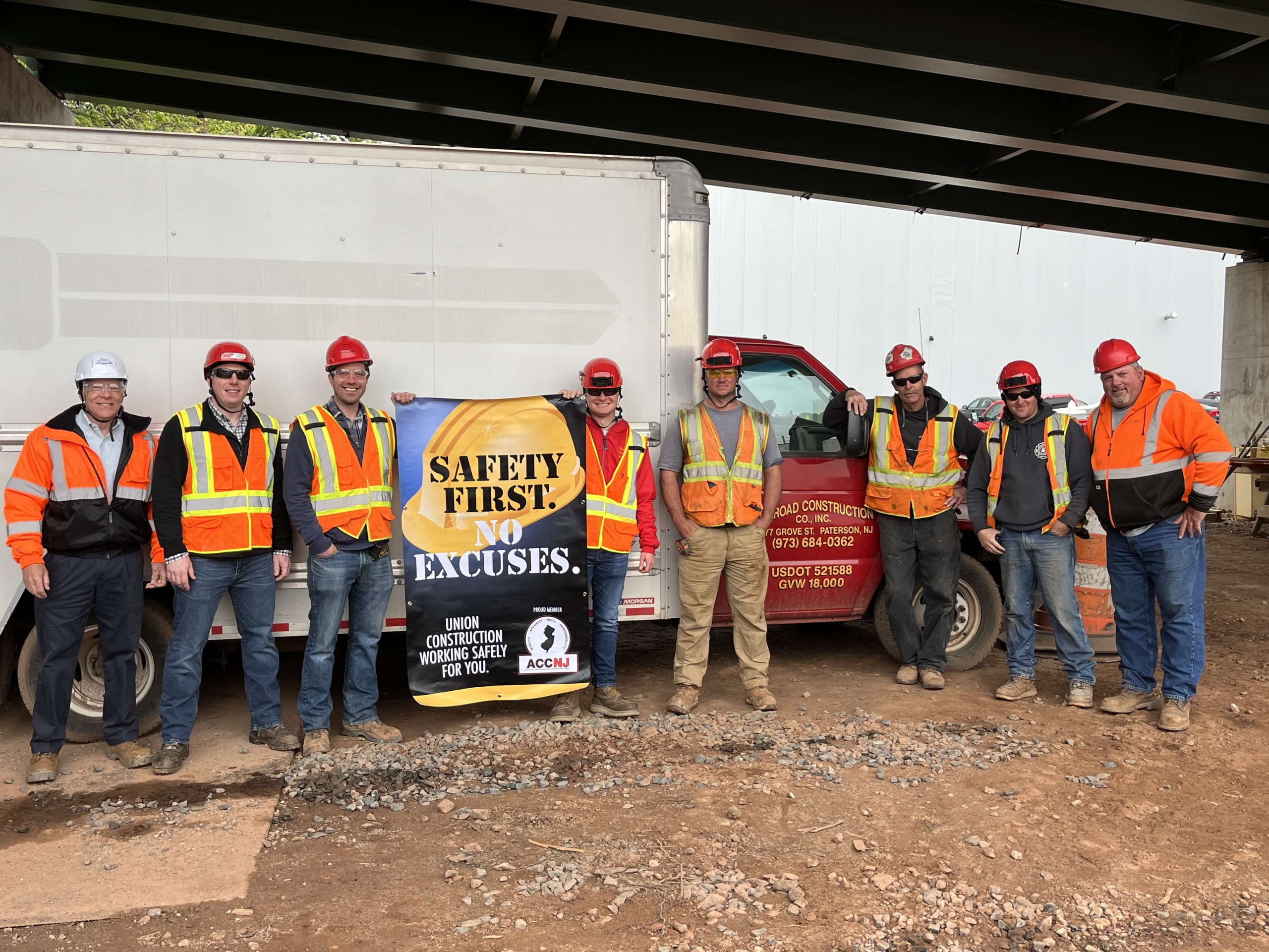 Men in vests and hats holding a safety first sign