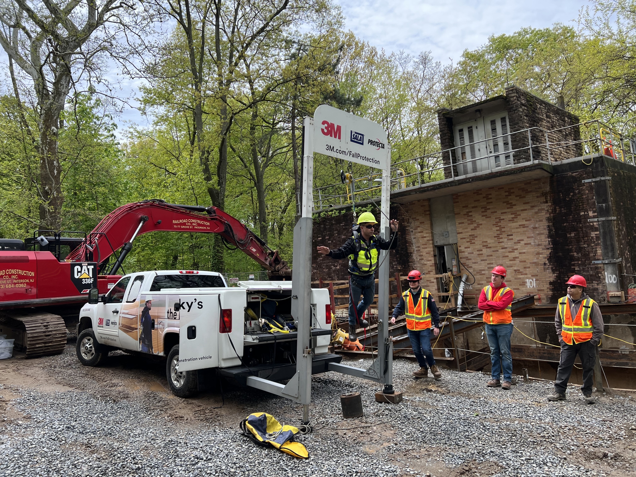 Picture of a man in a harness in a 3M Fall Protection machine and group surrounding him